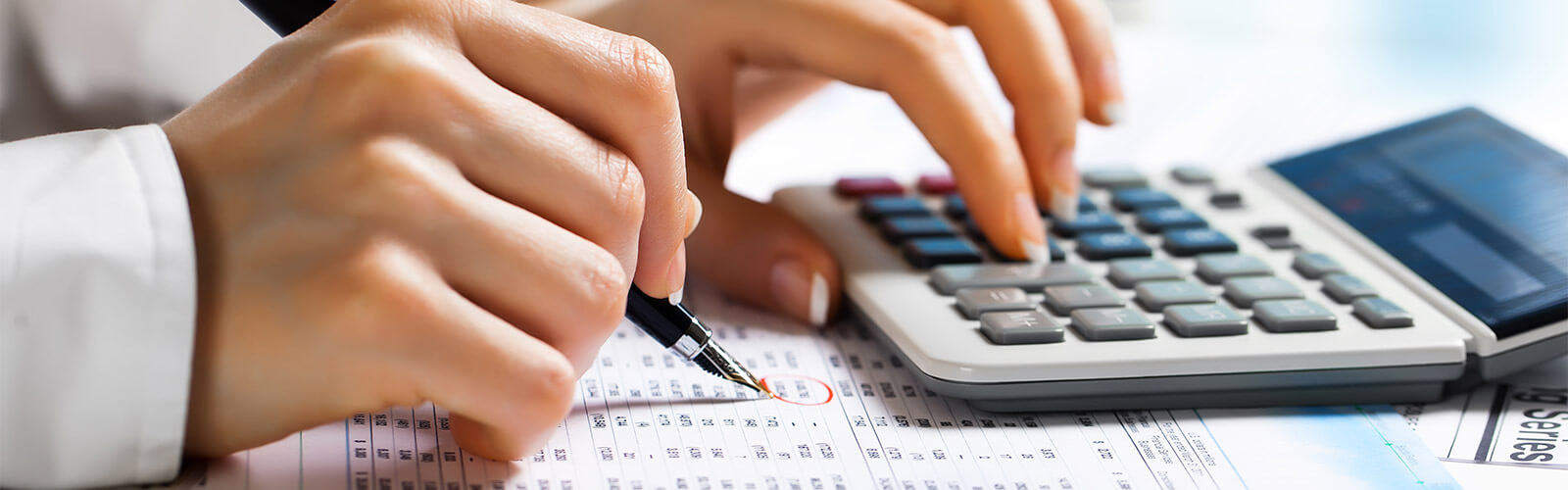 Accountant using calculator, pen and paper